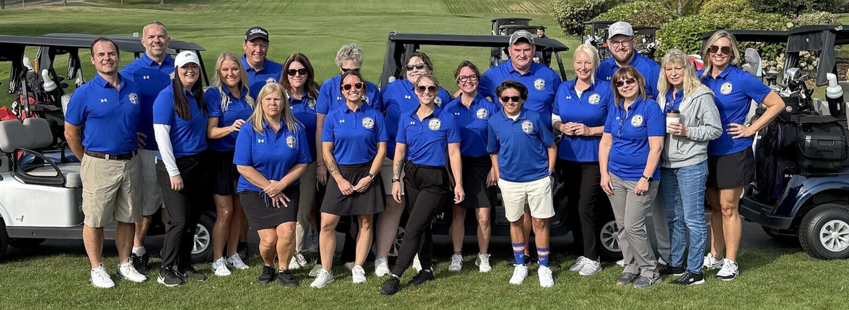 Many people posing for a picture on a golf course